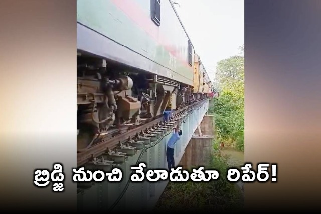 locopilots repain engine while dangling from bridge